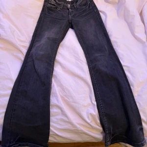 Svarta lowwaist bootcut jeans från Gina Tricot - Snygga svarta low waist bootcut jeans från Gina Tricot med en klassisk femficksdesign. De har en knapp- och dragkedjestängning framtill och är tillverkade i ett slitstarkt denimtyg.