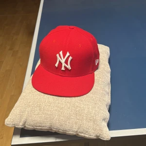 Röd keps från New Era - Snygg röd keps från New Era med broderad vit logga framtill. Kepsen är en del av 59FIFTY-serien.