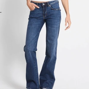 Blå bootcut jeans - Snygga blå bootcut jeans med femficksdesign och knappgylf. 