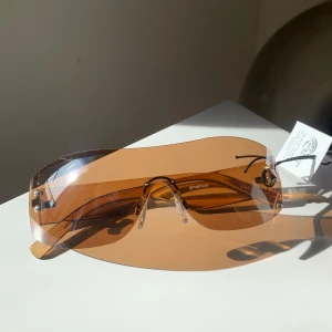 Bruna solglasögon från Ginatricot - Snygga bruna solglasögon från Ginatricot med en modern, oversized design. Rimless sunglasses. Tyvärr passar de inte mig därför säljer jag dom! Ordinariepris ca 130kr