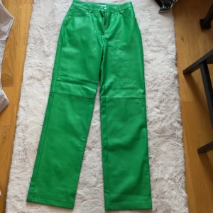 Gröna skinnbyxor - Snygga gröna skinnbyxor med hög midja och raka ben. Byxorna har en klassisk femficksdesign och stängs med dragkedja och knapp. Perfekta för att sticka ut med en färgglad stil.