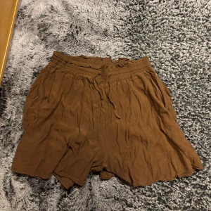 Bruna shorts från KappAhl - Säljer ett par bruna shorts från KappAhl i en avslappnad stil. De har en bekväm resårmidja med knytband. Perfekta för varma dagar! Skriv gärna om eventuella frågor.🌺