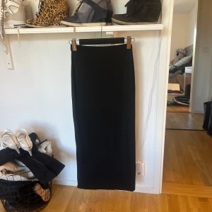 Svart långkjol - Elegant svart långkjol med en stilren design. Perfekt för en chic och minimalistisk look. Kjolen har en rak passform och är tillverkad i ett mjukt material som ger en bekväm känsla.