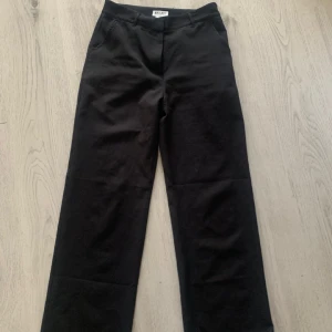 Svarta kostymbyxor från Madlady - Snygga svarta kostymbyxor från Madlady i storlek EU38. Byxorna har en klassisk design med raka ben och en bekväm passform. Ena knappen är av ( Se sista bilden ) Men dom funkar lika bra att använda endå det är inget som märks och går säkert att laga annars!