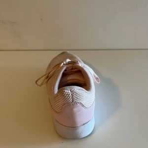 Rosa sneakers med snörning - Säljer ett par snygga rosa sneakers med snörning. Skorna har en stickad ovandel och en vit sula som ger en sportig look. Perfekta för en avslappnad stil.