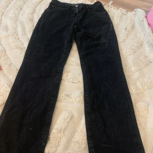 Svarta jeansbyxor - Säljer ett par svarta jeansbyxor med straight passform. De har en klassisk design med fem fickor och knappgylf. Perfekta för en avslappnad stil.