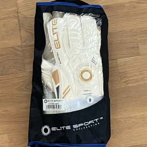 Vita målvaktshandskar från Elite Sport - Säljer ett par vita målvaktshandskar från Elite Sport med roll contact design. Handskarna har en stilren look med guld- och svarta detaljer samt justerbara handledsband för optimal passform. Perfekta för att ge ett bra grepp och skydd i målet. Storlek 9.