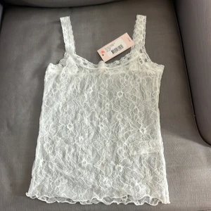 Vit spetslinne - vitt spetslinne med smala axelband. Linnet är genomskinligt och har ett fint blommönster i spetsen. Aldrig använt i small