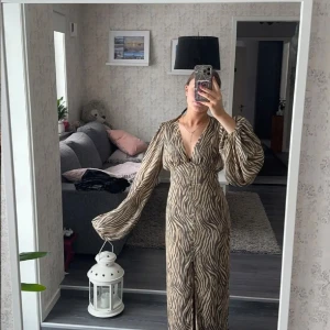 Adoore  - Snygg långklänning från adoore med zebramönster och v-ringning. Klänningen har långa, vida ärmar och knappar framtill. Perfekt för en trendig look! Säljer för 1500 bra pris till skillnad från vad andra har satt för pris!! 😊