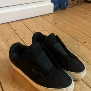 Svarta sneakers från Axel Arigato - Snygga svarta sneakers från Axel Arigato i mocka med en stilren design. Skorna har en vit sula och elastisk detalj över vristen för enkel påtagning. Perfekta för en avslappnad stil. Köpte dom för lite över 2000 kronor men säljer dom för 900. Men ni får gärna ge andra prisförslag!😊