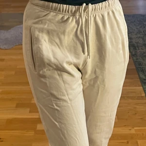 Beige mjukisbyxor från Lounge - Säljer ett par bekväma beige mjukisbyxor från Lounge. Byxorna har elastisk midja med snörning och muddar vid bensluten. Perfekta för en avslappnad dag hemma. Jag har knappt använt dessa, därför är de i nyskick. Snörena sitter på insidan av byxorna. De är beiga i storlek xs- oversize. Märket lounge står på vänstra benet. Väldigt ljus beige Nypris 700-800