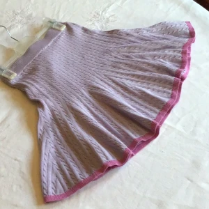 Lila stickad kjol från Monki - Säljer en söt lila stickad kjol från Monki med rosa kanter. Kjolen har ett ribbat mönster och en bekväm resår i midjan. Perfekt för en mysig och stilren look. 💜