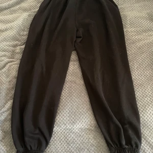 Svarta mjukisbyxor från Bershka - Säljer ett par svarta mjukisbyxor från Bershka med trycket 'New York' på ena benet. Byxorna har elastisk midja och muddar vid bensluten för en bekväm passform. Perfekta för en avslappnad stil.