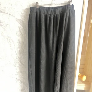 Svarta ribbade byxor - Snygga svarta byxor med ribbad textur och elastisk midja. Perfekta för en avslappnad stil med en loose passform. Inga fickor. 