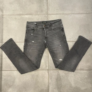 Jeans Jack & Jones - Snygga grå jeans från Jack & Jones med slitna detaljer. Slim/Glenn . De har en tight passform och är perfekta för en trendig look. Jeansen har en klassisk femficksdesign och knappgylf. Jag är 180 och väger 72✅💯Priset är ej hugget i sten🫡