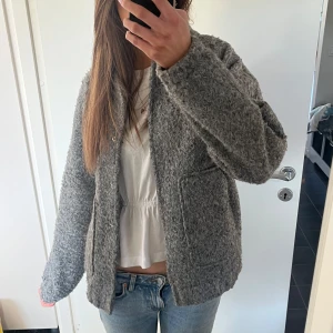 Grå ulljacka - Säljer en mysig grå ulljacka med knappar framtill. Jackan har en normal passform och långa ärmar. Den är stilren och enkel att matcha med olika outfits. Original pris 650 säljer för 350!! Knappt använd💕