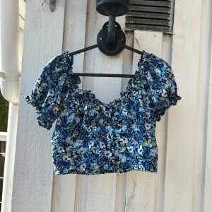 Blommig croppad topp - Blå blommig topp! Fin till vardagen och extra tillställningar. Använd men väl omhändertagen!