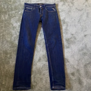 Blå jeans från Replay - Tvär fetta blå jeans från Replay med en klassisk femficksdesign och knappgylf. Jeansen har en stilren look med subtila slitningar och kontrastsömmar. Perfekta för en avslappnad stil. 8/10 i Skick Passar mig perfekt som är 177 cm lång 