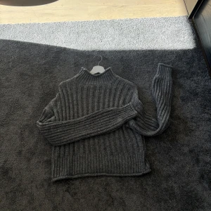 Grå ribbad stickad tröja från NLY Trend - Säljer en mysig grå stickad tröja från NLY Trend. Tröjan har en ribbad design och långa ärmar, perfekt för kyligare dagar. Den är i storlek S och passar utmärkt för både höst och vinter. Perfekt för att hålla sig varm och stilren!