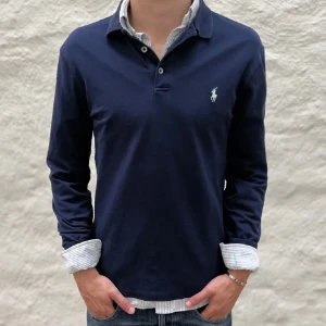 Ralph Lauren piké  - Säljer en stilren mörkblå pikétröja från Ralph Lauren med klassisk krage och knappar framtill. Tröjan har en broderad logotyp på bröstet och är perfekt för en avslappnad men ändå snygg look. Skick 9/10✅  Skriv vid frågor eller funderingar i DM🍾