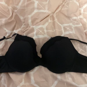 Svart sömlös bh från Emilia - Säljer en elegant svart sömlös bh från Emilia. Den har en stilren design med justerbara axelband och en bekväm passform. Perfekt för en smidig look under kläder. Ny med tagg kvar!