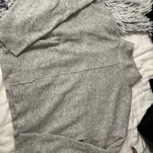 Grå stickad polotröja - Mysig grå stickad polotröja med ribbade detaljer vid ärmslut och nederkant. Perfekt för kyliga dagar och ger en stilren look. Passar bra till både jeans och kjol.