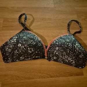 Helt ny blå och vitblommig bh från Esprit 75AA - Snygg blå bh från Esprit med blommigt mönster och rosa spetsdetaljer. Den har en liten rosett framtill och justerbara axelband för perfekt passform. Ingen vaddering. Aldrig använd, kommer från konkurslager. Kan skickas eller hämtas i Malmö. Nypris 199 kronor, kom med prisförslag.