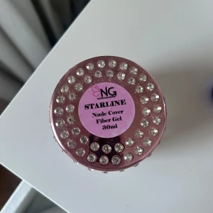 Nude Cover Fiber Gel 30ml - Nude Cover Fiber Gel från NG Starline i en lyxig burk dekorerad med strass. Gelen är medeltjock och innehåller glasfiber för extra styrka. Perfekt för att täcka missfärgade naglar och ge en naturlig nude look. Används efter Base Gel och härdas i LED eller UV lampa.