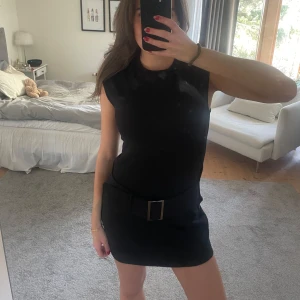 Svart ärmlös klänning med bälte - Snygg svart klänning med ett brett bälte i midjan. Perfekt för en stilren look. Klänningen har en kort längd och en enkel design som passar till många tillfällen. Säljer tyvärr då den är lite för stor på mig:(((❤️Endast använd 1 gång! Kolla beskrivningen innan du köper🩷