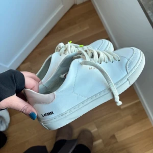 Axel Arigato, använt en gång - Snygga vita sneakers från Axel Arigato med diskret logga på sidan och häl. Skorna har vita snören och en cool leopardmönstrad innersula. Perfekta för en stilren look.