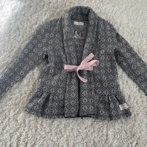 Odd Molly - Snygg mönstrad jacka från Odd Molly med ett rosa knytband framtill. Jackan har ett svartvitt mönster och långa ärmar. Storlek 0 (XXS-XS)