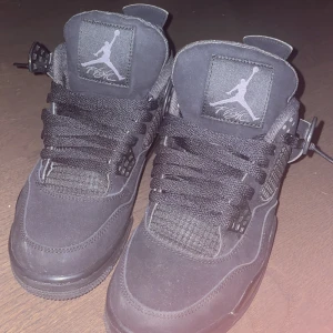 Air Jordan 4 - Snygga svarta Nike Air Jordans med klassisk design och ikonisk logga. Skorna har snörning och är tillverkade i mocka med detaljer i syntet. Älskar själv skorna men märkte passformen var för liten för mig.
