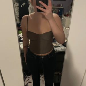 Brun korsettopp - Säljer en snygg brun korsettopp. Toppen har smala axelband och en figurnära passform som ger en stilren look. Perfekt för att lyfta vilken outfit som helst. Är i storlek M men det är ganska liten i storleken så skulle säga att den passar S mer. Aldrig använd så är i nyskick💖