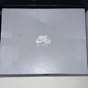 Svarta Nike Air Force 1 - Säljer ett par klassiska svarta Nike Air Force 1 sneakers. Skorna har en stilren design med snörning och är tillverkade i skinn. Perfekta för en casual look.