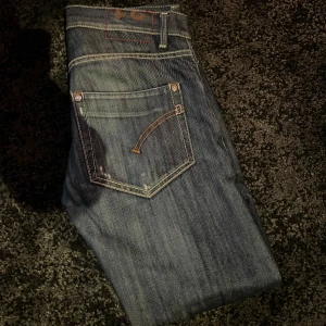 Dondup Jeans med slitningar - Snygga mörkblå jeans med coola slitningar och kontrastsömmar. Perfekta för en avslappnad stil. De har en klassisk femficksdesign och knappgylf.