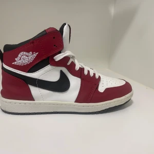 Nike Air Jordans i rött och vitt - Snygga Nike Air Jordans i en klassisk röd och vit färgkombination med svarta detaljer. Skorna har hög snörning och den ikoniska Air Jordan-loggan på sidan. Perfekta för dig som vill ha en stilren och sportig look.