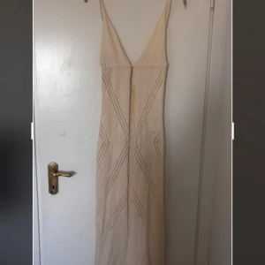 Stickad klänning  - Säljer beige lång stickad klänning med knytning i ryggen. Så fin och mjuk. Den är ej genomskinlig.