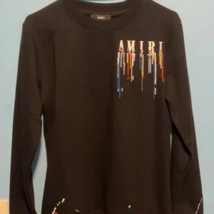 Amiri Tröja - Säljer en svart långärmad tröja från Amiri med coolt broderat mönster i flera färger. Perfekt för att ge din outfit en unik touch. Tröjan är helt ny aldrig använd, TAG FORTFARANDE KVAR. Passar S/M. Kontakta vid intresse