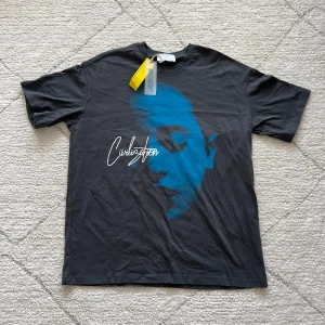 Svart t-shirt med blått tryck från Only - Säljer en svart t-shirt från Only med ett stort blått ansiktstryck och texten 'Civilization' på framsidan. Baksidan har texten 'Censored'. T-shirten är kortärmad och har en normal passform. Perfekt för en avslappnad stil.