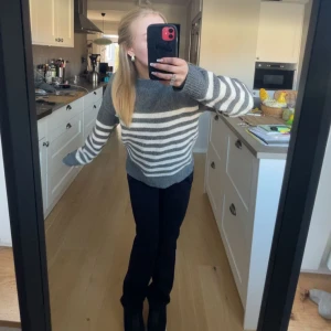 Grå och vit randig stickad tröja - Säljer en mysig stickad tröja i grått och vitt med breda horisontella ränder. Tröjan har lång ärm, rund halsringning och en relaxed passform. Perfekt för kyliga dagar!