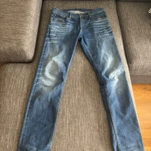 Blå jeans från Lindbergh - Snygga blå jeans från Lindbergh med klassisk femficksdesign. Jeansen har normal passform och raka ben, perfekt för en stilren look. Märkespatch i läder baktill i midjan och knappgylf framtill. W 32, L 34. Nypris 1200.