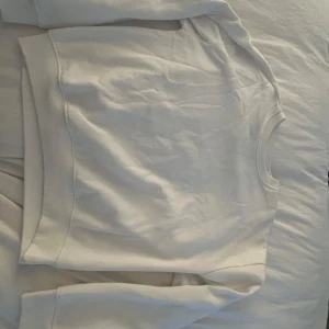 Vit sweatshirt från 157 - Säljer en enkel och stilren vit sweatshirt från 157. Tröjan har rund halsringning och långa ärmar. Perfekt basplagg att ha i garderoben.