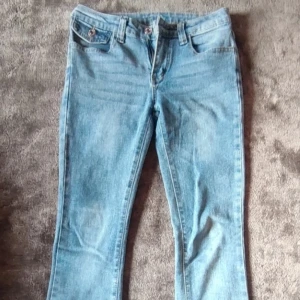 Ljusblå jeansbyxor med raka ben - Säljer ett par klassiska ljusblå jeansbyxor med raka ben och normal passform. Byxorna har framfickor och bakfickor med lock och knapp. Perfekta till vardags och enkla att matcha med olika toppar.