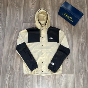 Beige och svart vindjacka från The North Face - Säljer en beige och svart vindjacka från The North Face. Jackan har en justerbar huva och dragkedja framtill. Den är i perfekt skick. Fråga om du har frågor