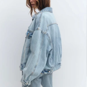 Oversized ljusblå jeansjacka - Säljer en oversized ljusblå jeansjacka med klassisk krage och knäppning framtill. Jackan har två bröstfickor med lock och knappar samt raka ärmar. Perfekt för en avslappnad och trendig look.