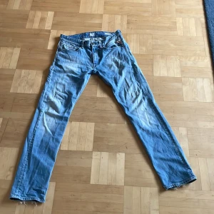 Blå Replay Jeto jeansbyxor - Säljer ett par klassiska blå jeans från Replay, modell Jeto. Byxorna har raka ben, med tydliga slitningar 