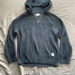 Mörkblå stickad hoodie från Pepe Jeans - Säljer en mörkblå stickad hoodie från Pepe Jeans i storlek L. Tröjan har dragkedja vid halsen, ribbade muddar och en stor huva. Perfekt för dig som gillar en avslappnad och stilren look.