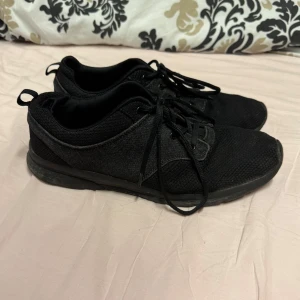 Svarta sneakers - Säljer ett par svarta sneakers med snörning.  Perfekta för vardagsbruk och träning. Storlek 45