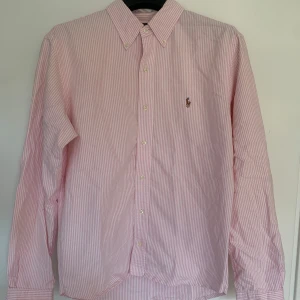 Rosa och vit randig skjorta från Ralph Lauren - Säljer denna fina skjorta från från Ralph Lauren, som är perfekt nu till sommaren! Den är i storlek S, i en custom-fit, som jag sedan sytt in litegrann på vardera sida för att sitta lite smalare. Detta går lätt att ta bort om så önskas, bara att använda sprätt i några minuter. Kan också själv fixa det vid köp om det skulle viljas. Riktigt bra skick! Hör av dig vid frågor eller om du vill ha fler bilder😁