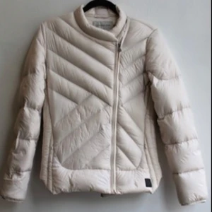 Beige jacka  från Calvin Klein - Säljer en stilren beige jacka från Calvin Klein. Jackan har en quiltad design med dragkedja framtill och en liten CK-logga på sidan. Perfekt för kyligare dagar med sin långa ärmar och bekväma passform.